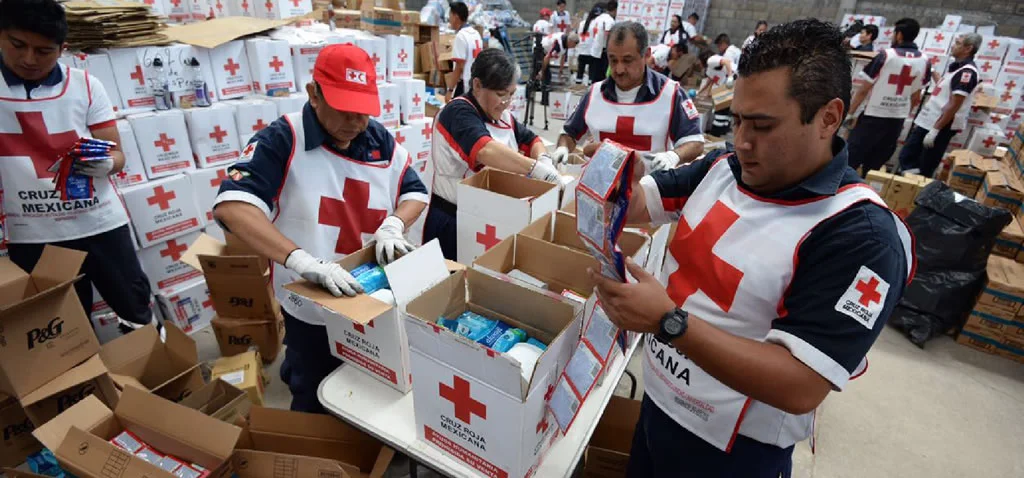 Voluntarios clasificando cajas de ayuda humanitaria en un centro de acopio.